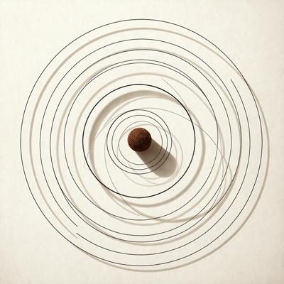 The primary subject of the image is a small brown ball, which is placed in the center of a circle. The circle is made up of several lines, creating a patterned appearance. The setting is a white surface, which provides a clean and minimalistic backdrop for the ball and the circle. The visual style of the image is a combination of digital art and illustration, as the lines and the ball are both depicted in a detailed and artistic manner. The colors and mood of the image are predominantly white and neutral,